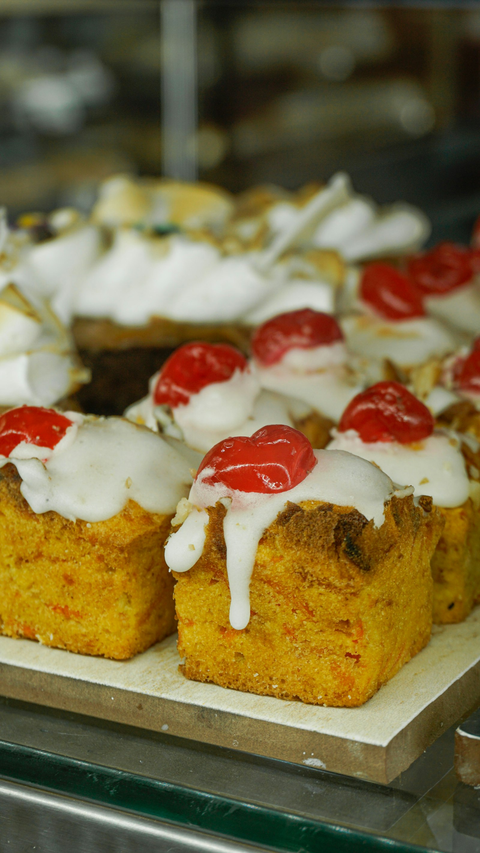 Vitrina de panadería con pan dulce decorado con betún y cerezas